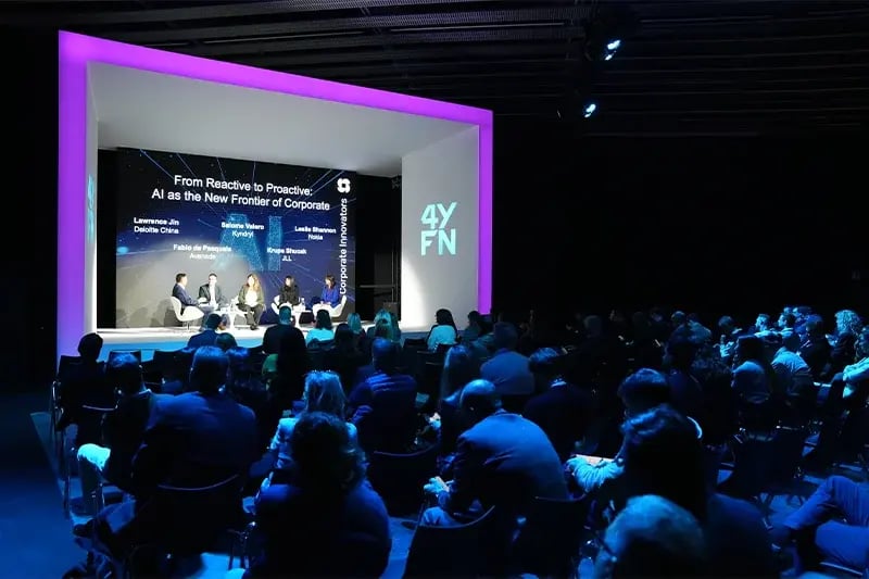 Wide-angle view of a packed audience attending a 4YFN Corporate Innovation panel discussion titled "From Reactive to Proactive: AI as the New Frontier of Corporate," featuring five speakers on a modern, neon-lit stage.