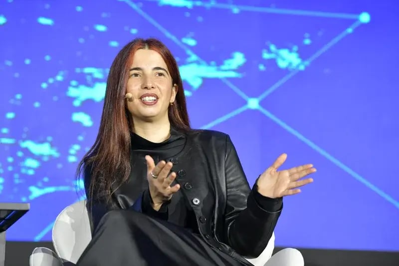 Woman speaking on stage at 4YFN, gesturing during a discussion against a blue digital network backdrop.